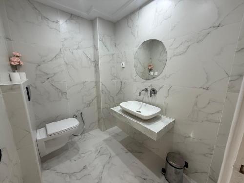 a white bathroom with a sink and a mirror at Yocca Hotel Residence in Hammamet