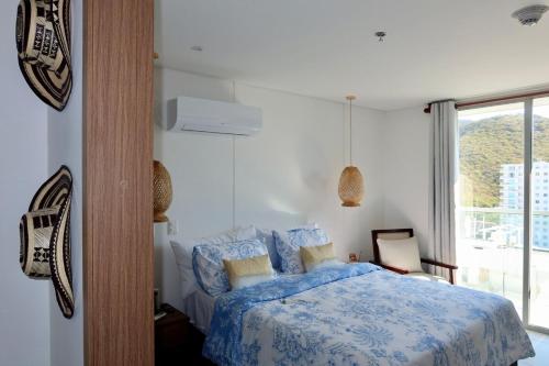 a bedroom with a bed with a blue comforter and a window at Rodadero Ocean View Luxury Apt with Rooftop Pool in Taganga