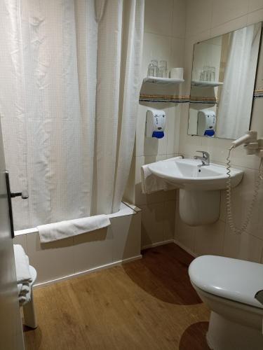 a bathroom with a sink and a toilet and a mirror at Hotel Europa in Girona