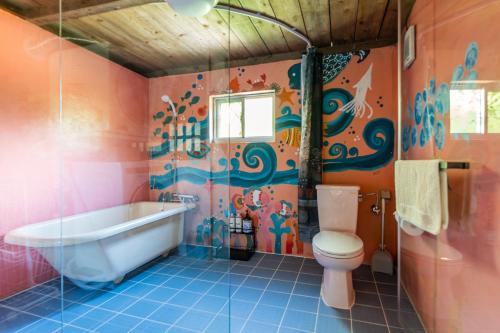 a bathroom with a bath tub and a toilet at 一棟貸し古民家月の桃 in Motobu