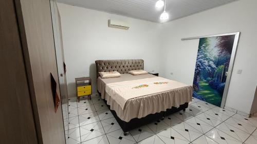 a bedroom with a bed and a painting on the wall at Casa inteira in Coxim