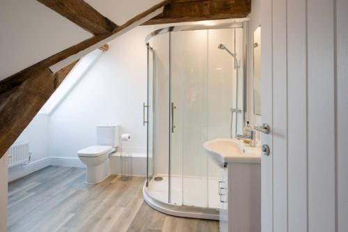 a bathroom with a shower with a toilet and a sink at Ploughman’s Green, Blythburgh in Halesworth