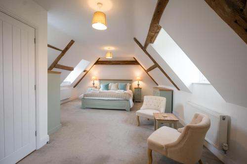 a bedroom with a bed and chairs in a attic at Ploughman’s Green, Blythburgh in Halesworth