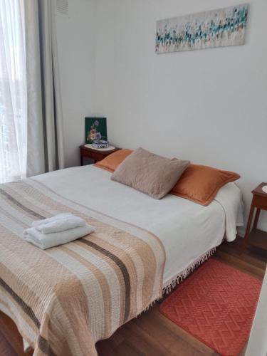 a bedroom with a large white bed with a red rug at Departamento, Chillan in El Cerrillo