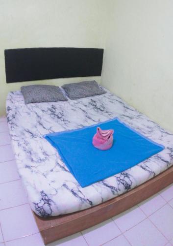 a bed with a pink hat on a blue blanket at Wisma Dahlia in Maumere