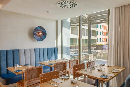 a restaurant with wooden tables and chairs and a large window at The Editory Ocean Way Funchal in Funchal