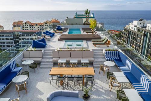 a rooftop patio with tables and chairs and the ocean at The Editory Ocean Way Funchal in Funchal