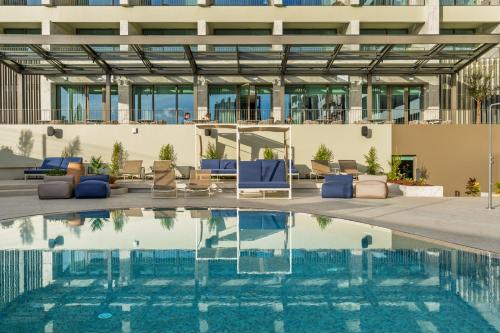 a swimming pool with blue chairs and a building at The Editory Ocean Way Funchal in Funchal