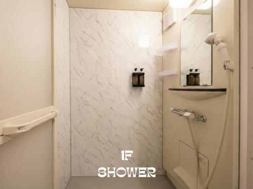 a shower in a bathroom with a white marble wall at MEME Villa 5BR - 3 Separate Toilets & 3 Showers - 10Gbps Wifi in Tokyo