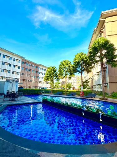 a swimming pool in a building with palm trees at SMDC Cheer residences-ZKL SUITES in Marilao