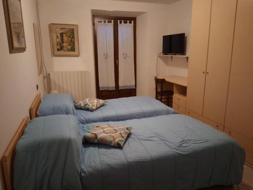two blue beds in a room with a desk at Affittacamere Ossola in Domodossola