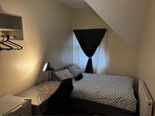 a small bedroom with a bed and a window at Lubona Stirchley Guest House in Birmingham
