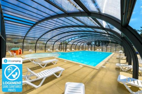 a swimming pool with a retractable roof and lounge chairs and a swimming pool at Chalet 3 étoiles - Piscine - ccbbhfa in Clohars-Carnoët
