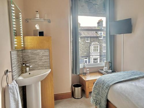 a bathroom with a sink and a bed and a window at Melrose Guesthouse in Ambleside