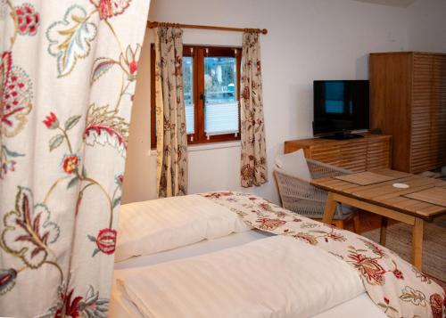 a room with a bed and a table and a window at Seehütte Tamberger in Feld am See