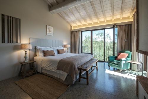 ein Schlafzimmer mit einem großen Bett und einem grünen Stuhl in der Unterkunft Borgo 69 Villas & Suites in Foiano della Chiana