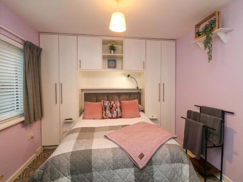 a bedroom with a bed with pink walls and white cabinets at Long Jack's in Ballygarrett