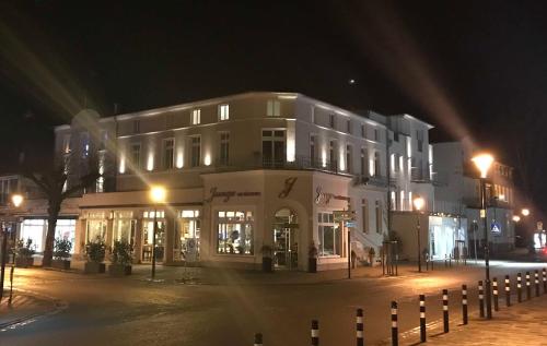a large white building on a street at night at Residenzen am Kirchenplatz in Warnemünde