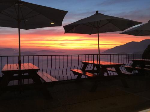 two tables and umbrellas on a balcony with a sunset at Cingjing Four Seasons B&B in Renai