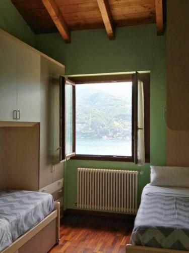 a green room with two beds and a window at Between mountains and lake in Carate Urio