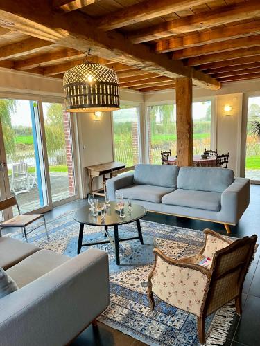 a living room with couches and a table and chairs at La Ferme de Beauvoorde - 13 personnes in Steenvoorde