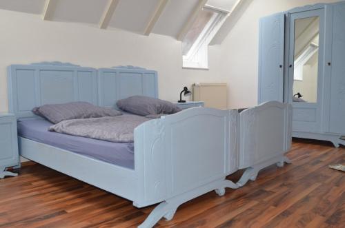 a white bed in a room with a wooden floor at Gästehaus Peter in Mettlach