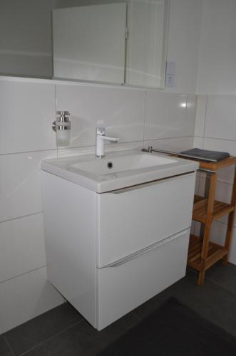 a white bathroom with a sink and a mirror at Gästehaus Peter in Mettlach