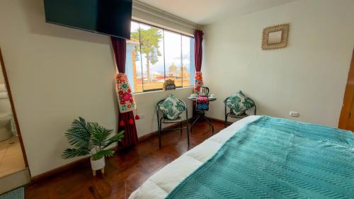 a bedroom with a bed and two chairs and a window at Apart Hotel de Alegria in Cusco