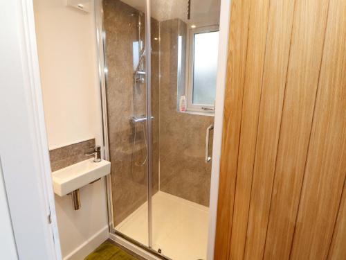 a shower with a glass door next to a sink at Westerlodge in Keswick