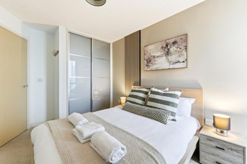 a bedroom with a large white bed with towels on it at Sleek Apartment with Balcony - City Centre - Free Parking, Fast WiFi and 55'' Smart TV by Yoko Property in Milton Keynes