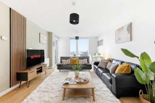 a living room with a black couch and a tv at Sleek Apartment with Balcony - City Centre - Free Parking, Fast WiFi and 55'' Smart TV by Yoko Property in Milton Keynes