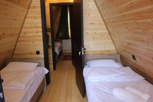 two beds in a room with wooden walls at Zaga Cottage in Kazbegi