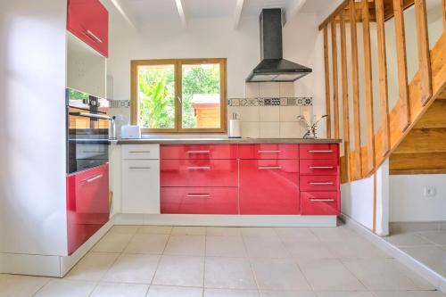 a kitchen with red cabinets and a window at Le chalet sur Manoire in Saint-Laurent-sur-Manoire