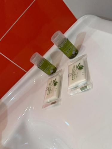 two bottles of green liquid sitting on top of a white sink at B&B Sud Est in Carmiano