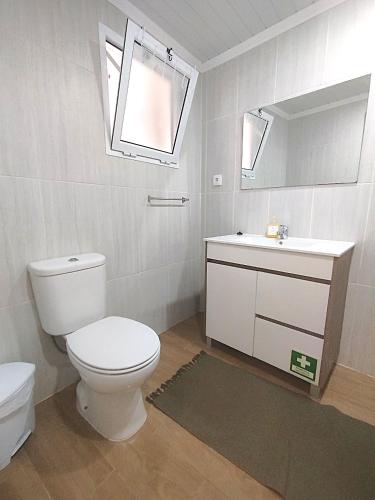 a bathroom with a toilet and a sink and a mirror at Casa do Portinho - Sea View House - in São Roque