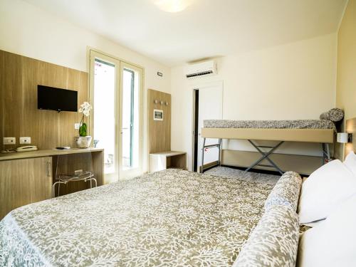 a bedroom with a bed and a desk and a window at Fruit Village Torre dell'Orso La Brunese 4stelle in Torre dell'Orso