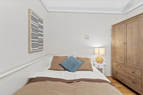 a white bedroom with a bed and a cabinet at Bright City Hideaway, Augarten and Danube - 5 min Metro - 10 min Center in Vienna