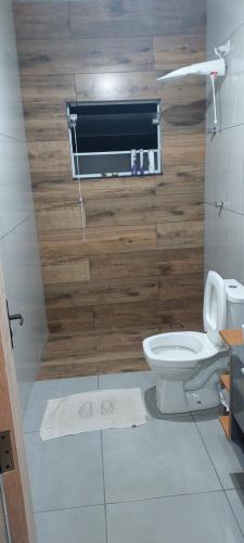 a bathroom with a toilet and a wooden wall at Casa Condomínio Ninho Verde II in Pardinho