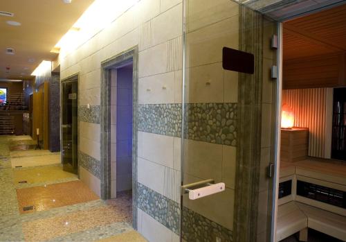a bathroom with a glass door with tiles on the wall at Hotel Mirta - San Simon Resort in Izola