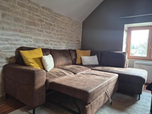 a living room with a brown couch with yellow pillows at Gîte du Ka'lao in Saint-Julien