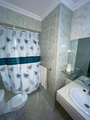 a bathroom with a sink and a toilet and a shower curtain at Pousada do Norte, ilha do Fogo in Calheta