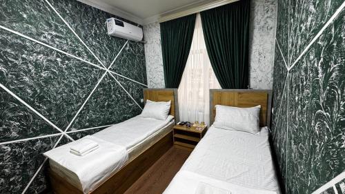 two beds in a room with green walls at Over City Hostel in Margilan