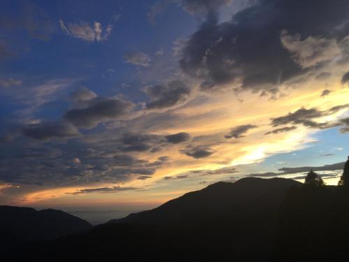 a sunset over the mountains with a cloudy sky at Cingjing Four Seasons B&B in Renai