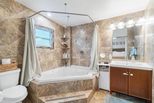 a bathroom with a tub and a toilet and a sink at Shady Banks Oasis in Fort Lauderdale
