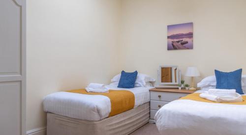 two twin beds in a room with a mirror at Crummock at the Graythwaite Estate in Sawrey