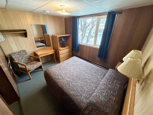 a bedroom with a bed and a chair and a window at Airport Chalet in Whitehorse