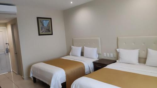 a hotel room with two beds with white and brown sheets at Hotel Del Viajero in Ciudad del Carmen