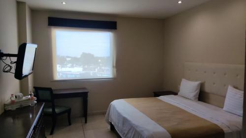 a bedroom with a bed and a desk and a window at Hotel Del Viajero in Ciudad del Carmen