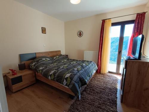 a bedroom with a bed and a tv and a window at Νύμφη Ηχώ, Θέα στα βουνά κάτω από το Ρολόι in Dimitsana