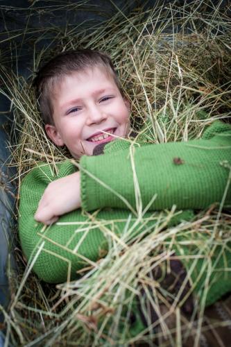 a young boy laying in a nest of hay at Ferien Bauernhof Maurachhof in Sankt Johann im Pongau